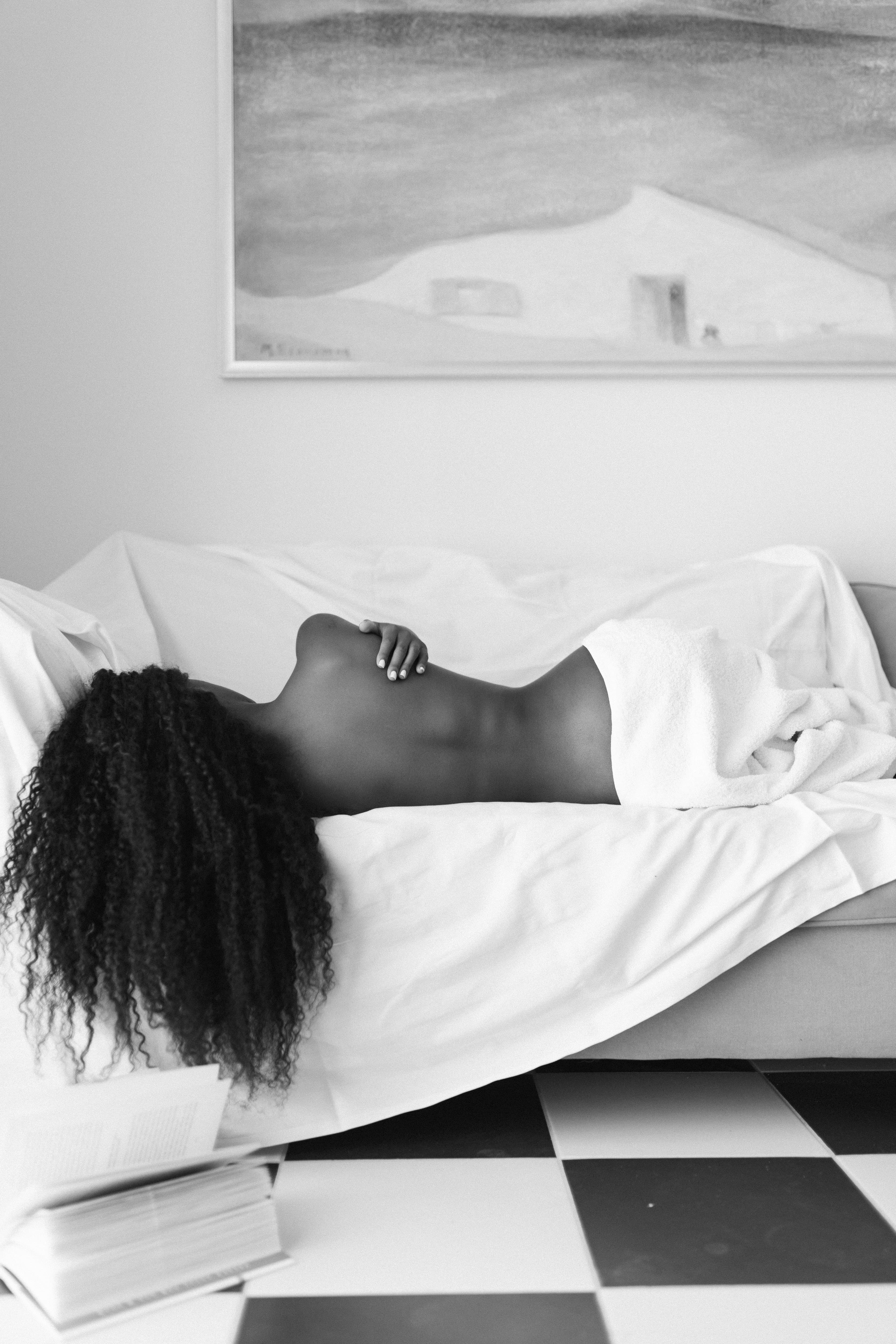 Black and white photograph from the series I Used to Be Her, a figure reclining beneath white linen